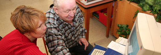 Darstellung der Hilfe für eine ältere Person am Computer.